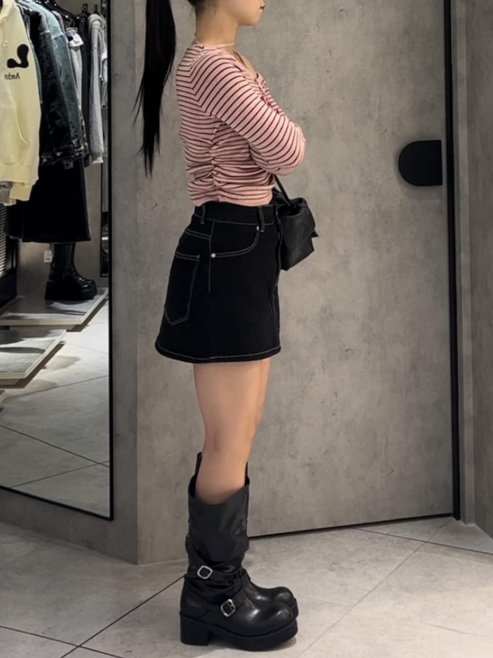 ピンク系のニット/セーター、ブルー系のスカート、ブラウン系のハンドバッグを着用したレディースの冬コーディネートの2枚目の写真