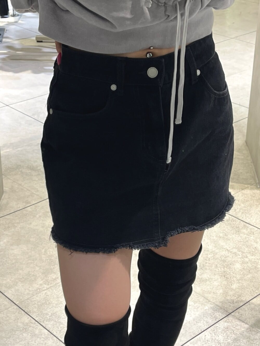 ブラック系のブーツ、グレー系のパーカー、ブラック系のスカートを着用したレディースの秋コーディネートの8枚目の写真