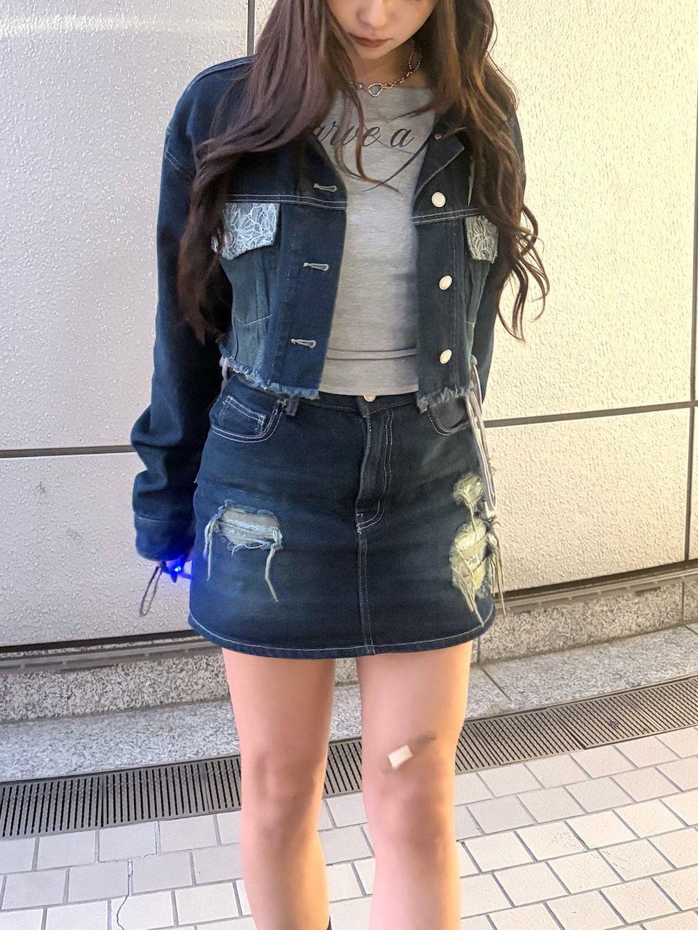 ブルー系のスカート、ブラック系のブーツ、グレー系のTシャツ/カットソーを着用したレディースの秋コーディネートの7枚目の写真