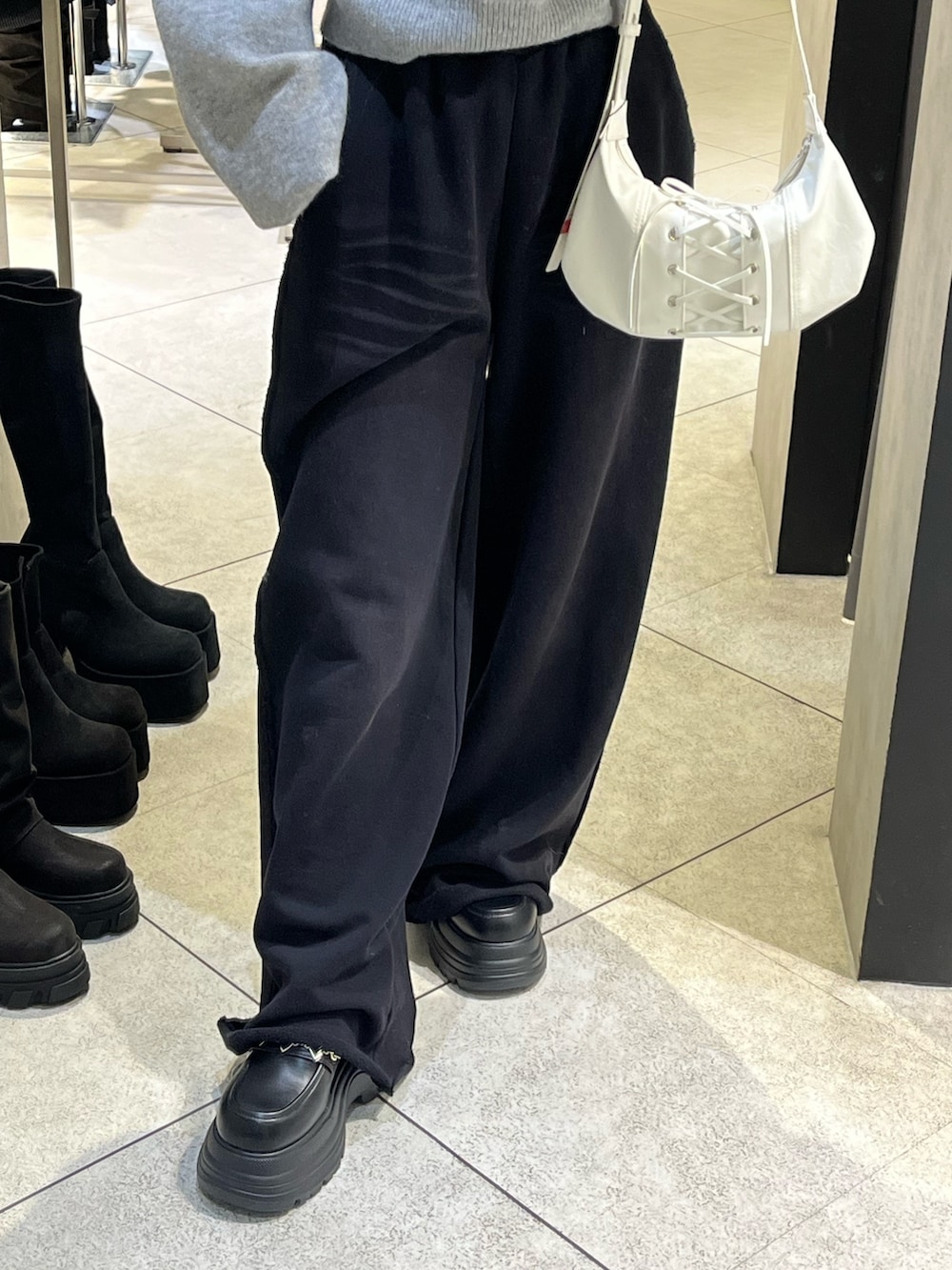 グレー系のパーカー、ブラック系のローファー、ホワイト系のショルダーバッグを着用したレディースの冬コーディネートの8枚目の写真