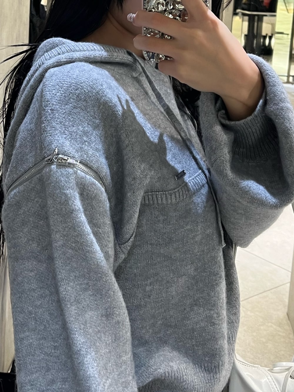 グレー系のパーカー、ブラック系のローファー、ホワイト系のショルダーバッグを着用したレディースの冬コーディネートの9枚目の写真