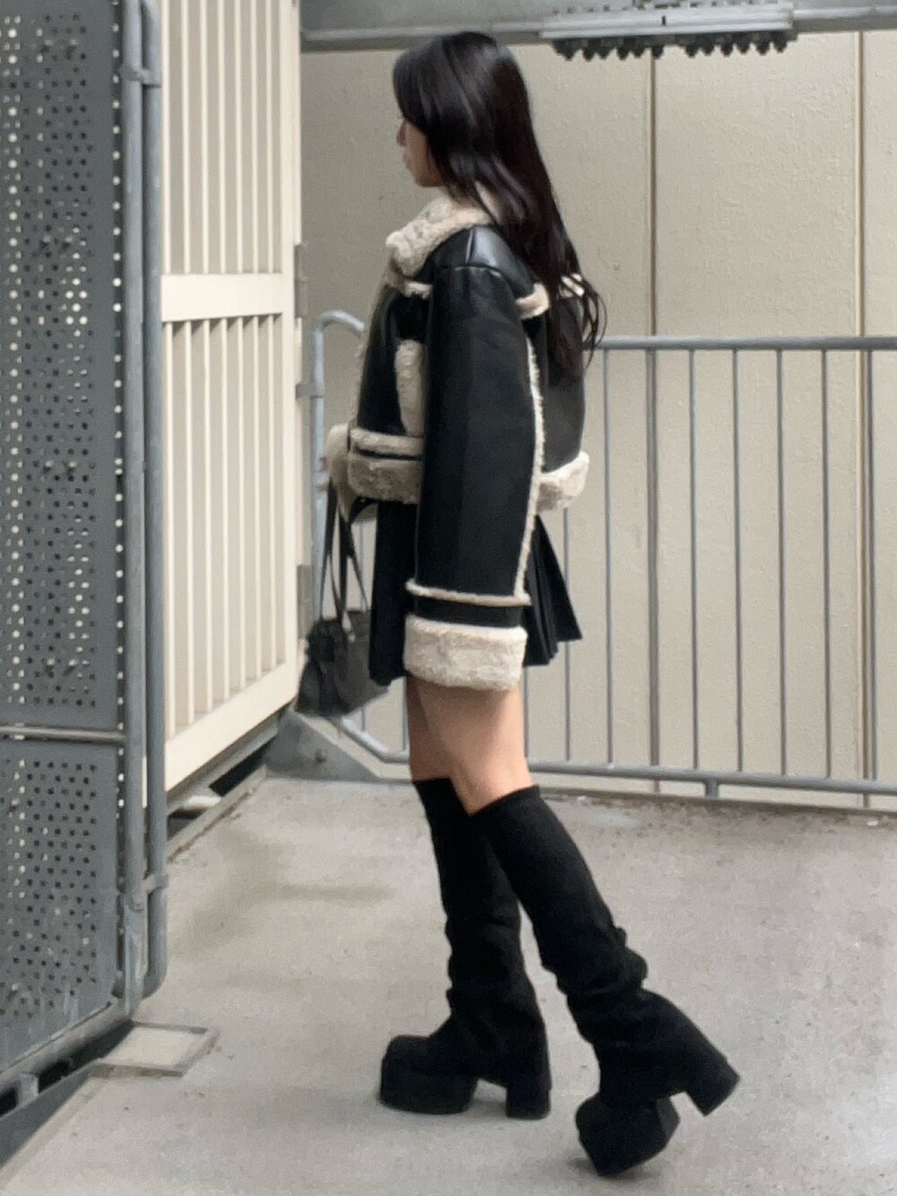 ブラック系のショルダーバッグ、ブラック系のブーツ、ブラック系のスカートを着用したレディースの秋コーディネートの2枚目の写真