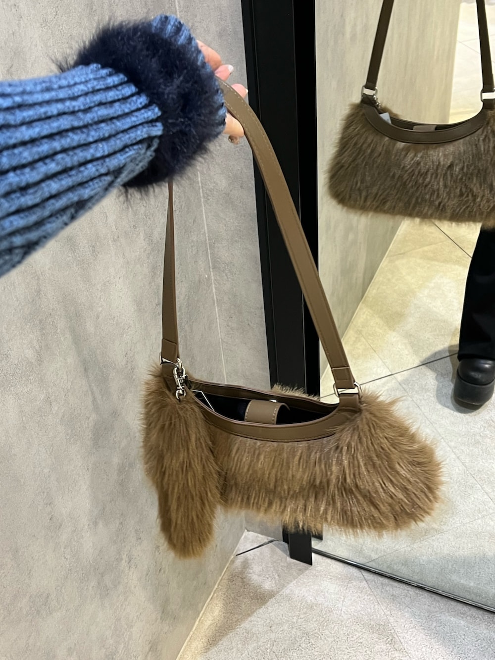 ブルー系のニット/セーター、ブラック系のデニムパンツ、ベージュ系のショルダーバッグを着用したレディースの冬コーディネートの10枚目の写真