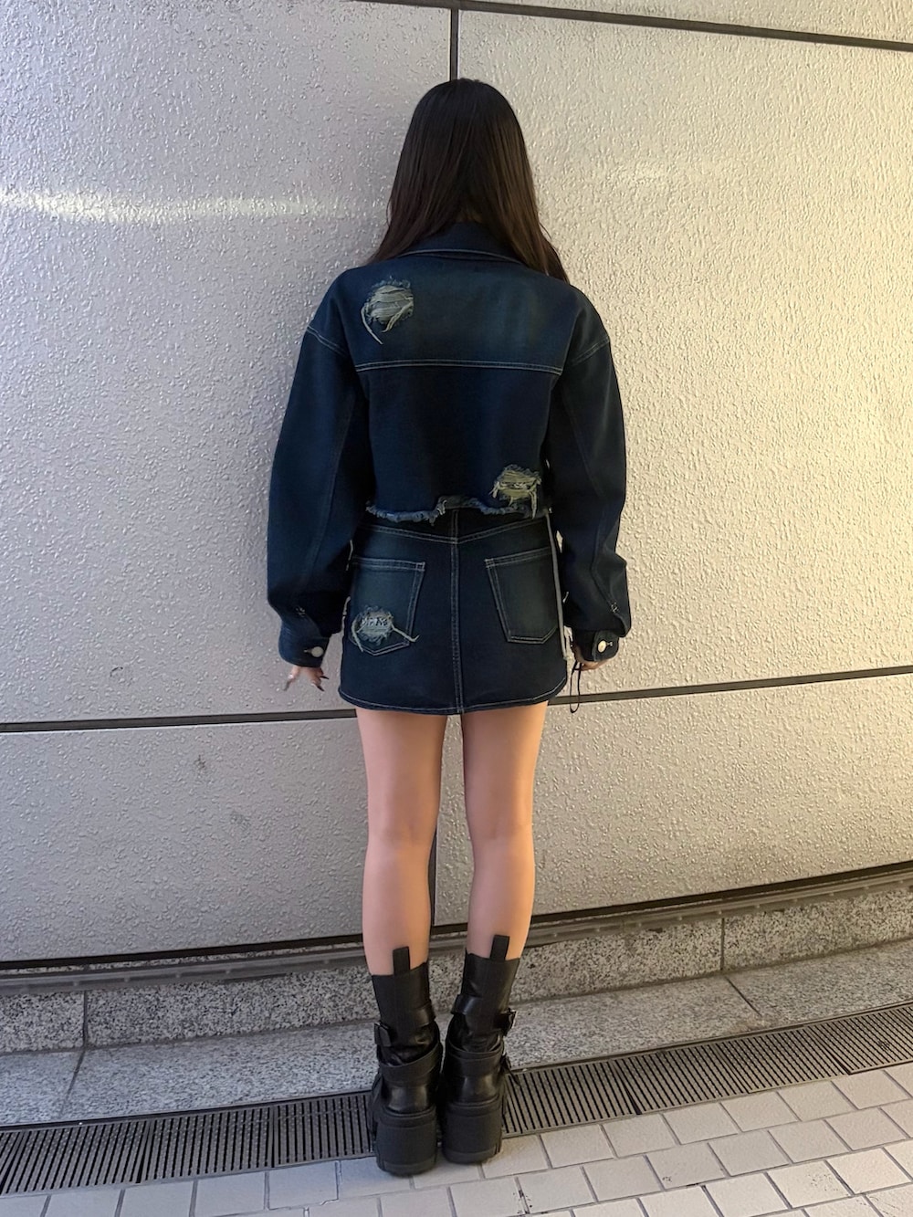 ブルー系のスカート、ブラック系のブーツ、グレー系のTシャツ/カットソーを着用したレディースの秋コーディネートの5枚目の写真