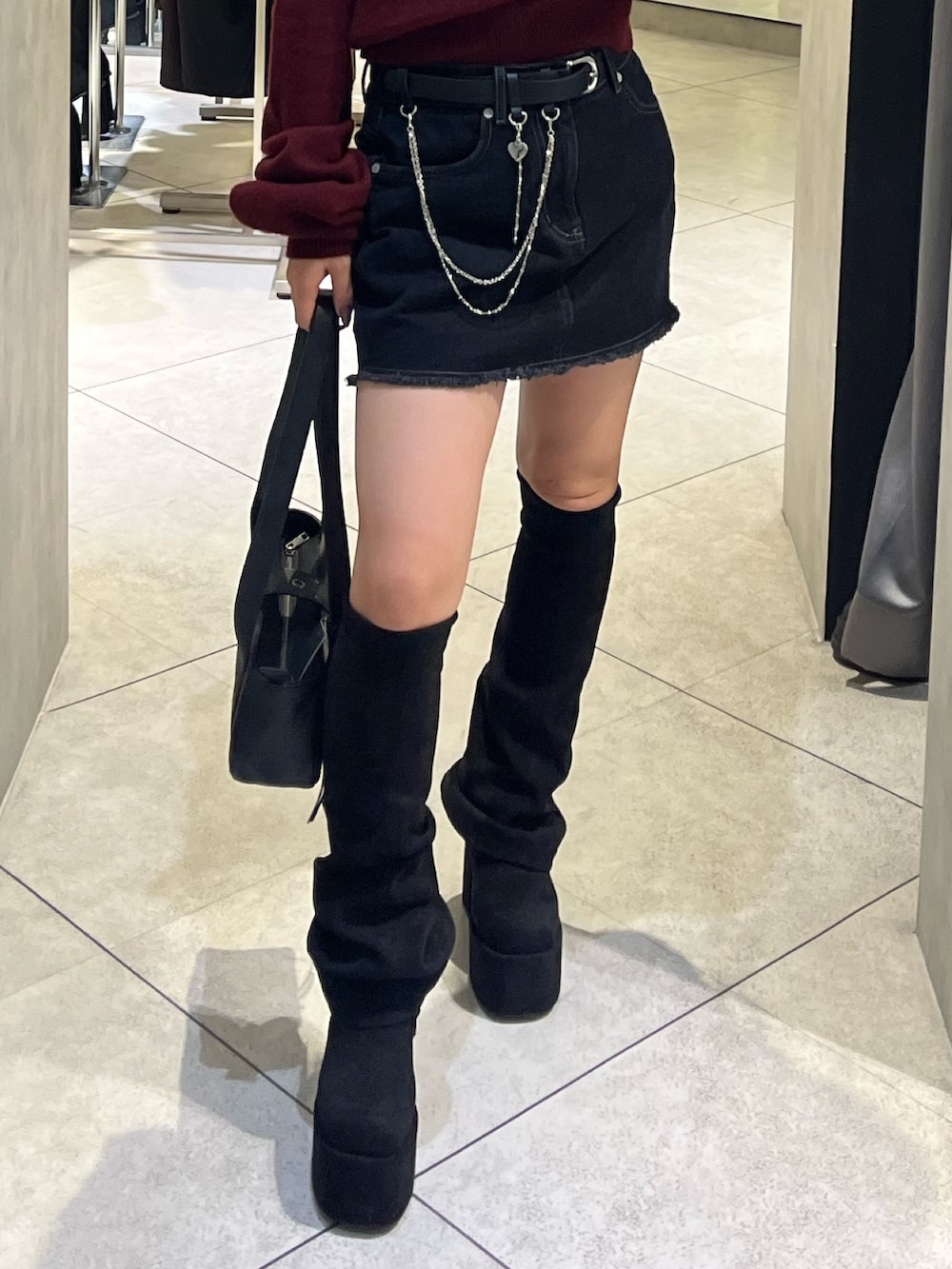 ブラック系のスカート、ブラック系のハンドバッグ、ブラック系のブーツを着用したレディースの秋コーディネートの8枚目の写真