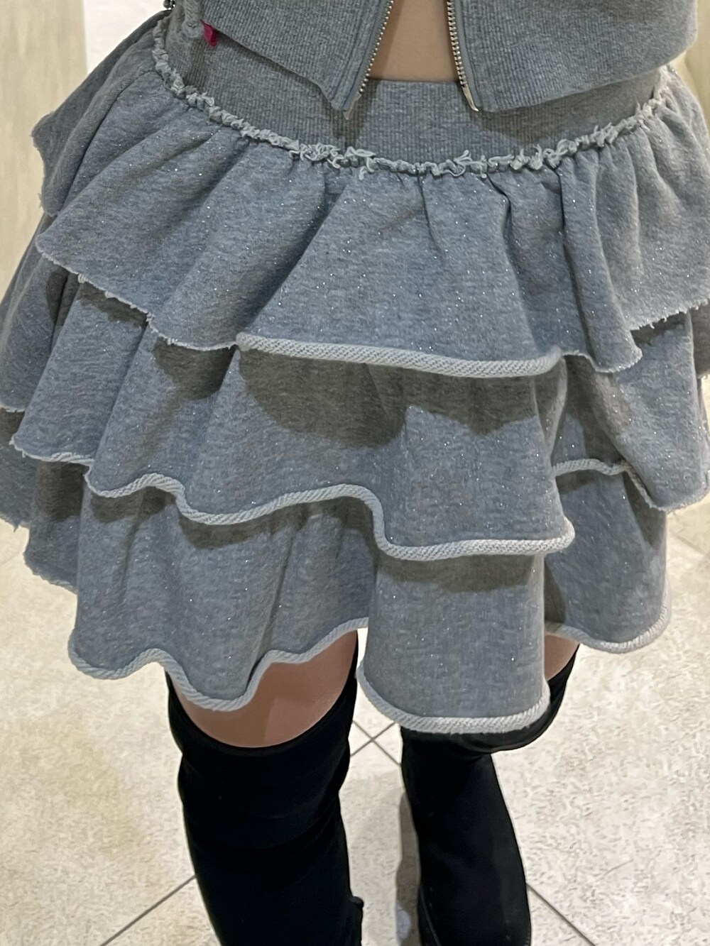 グレー系のパーカー、グレー系のスカート、ブラック系のショルダーバッグを着用したレディースの秋コーディネートの6枚目の写真