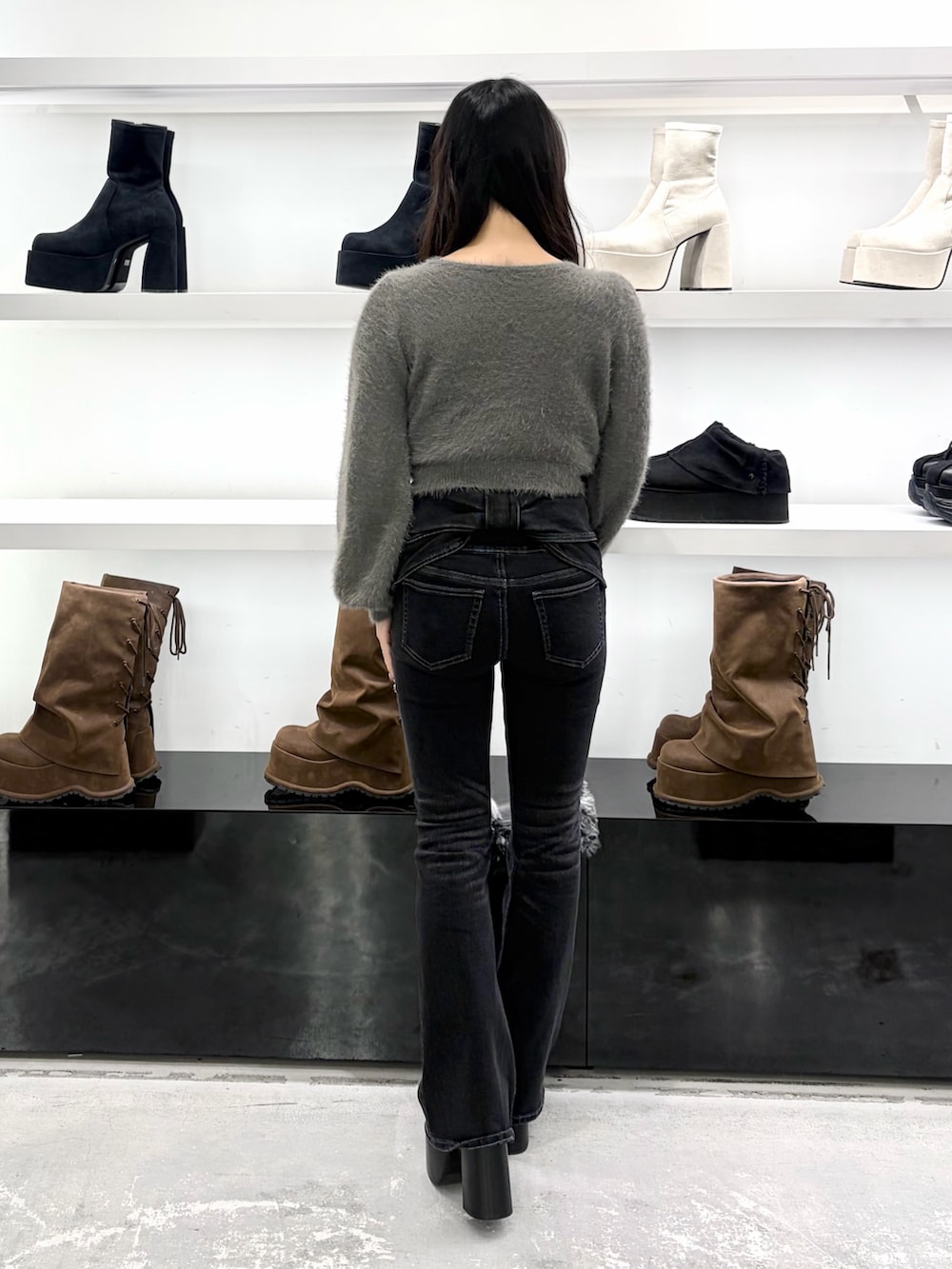 グレー系のニット/セーター、ブラック系のデニムパンツ、ブラック系のショルダーバッグを着用したレディースの秋コーディネートの4枚目の写真