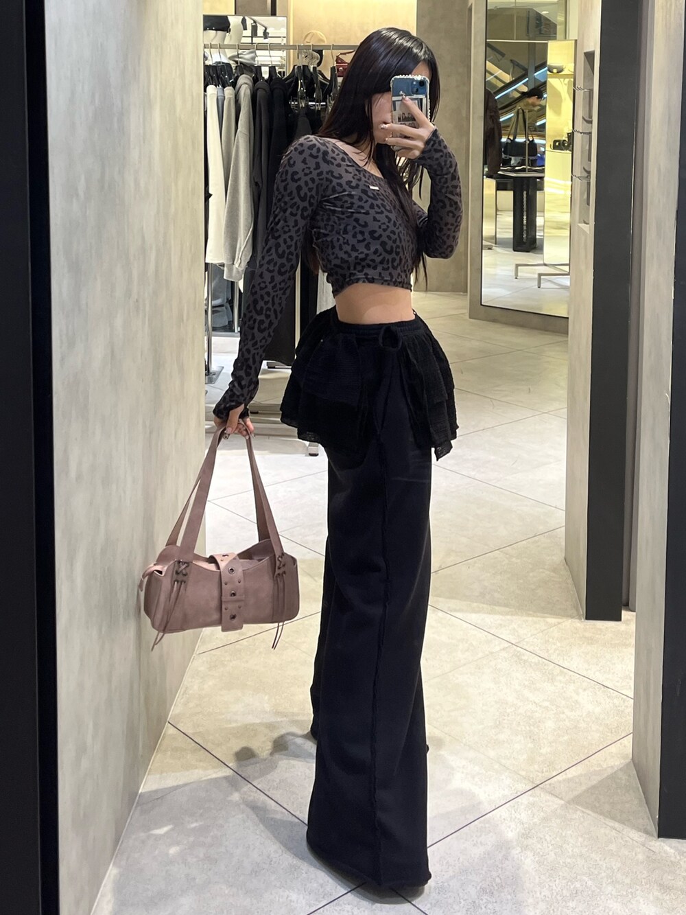 ブラック系のスカート、ブラック系のスウェットパンツ、ピンク系のハンドバッグを着用したレディースの秋コーディネートの2枚目の写真