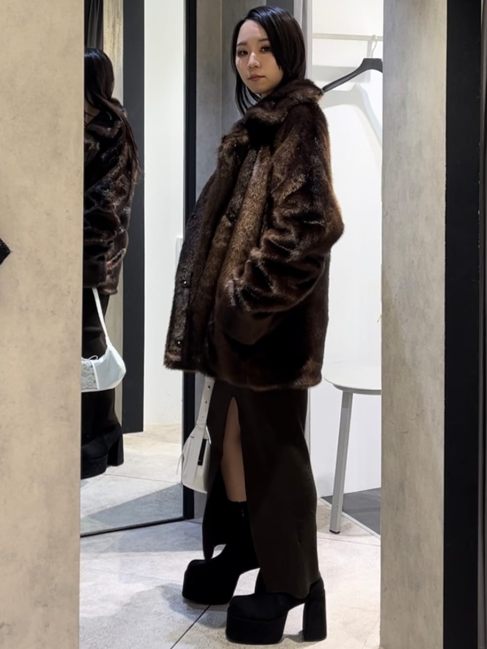 ブラウン系のその他アウター、ホワイト系のショルダーバッグ、ブラック系のブーツを着用したレディースの冬コーディネートの2枚目の写真