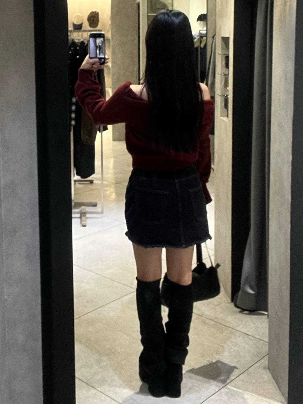 ブラック系のスカート、ブラック系のハンドバッグ、ブラック系のブーツを着用したレディースの秋コーディネートの3枚目の写真