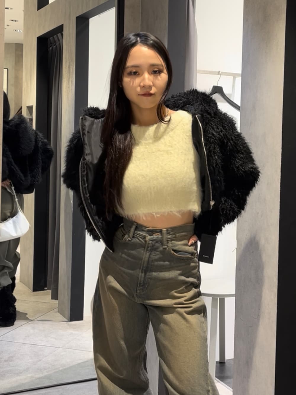 ブラック系のブルゾン、ホワイト系のニット/セーター、ブルー系のデニムパンツを着用したレディースの冬コーディネートの5枚目の写真