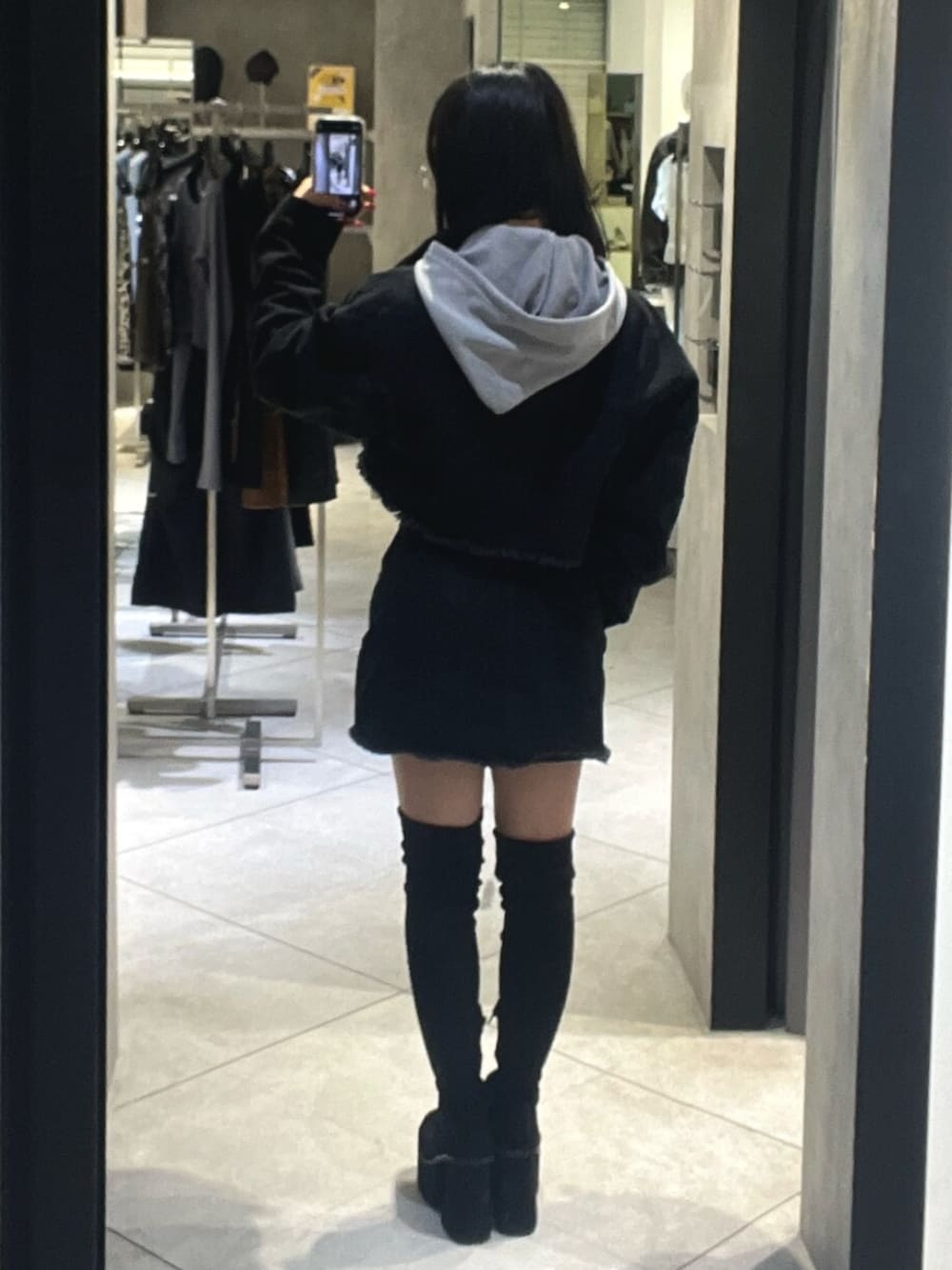 ブラック系のブーツ、グレー系のパーカー、ブラック系のスカートを着用したレディースの秋コーディネートの3枚目の写真