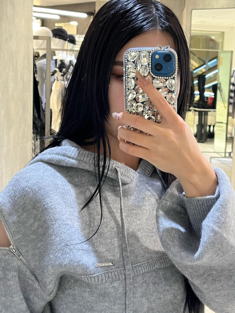 グレー系のパーカー、ブラック系のローファー、ホワイト系のショルダーバッグを着用したレディースの冬コーディネートの7枚目の写真