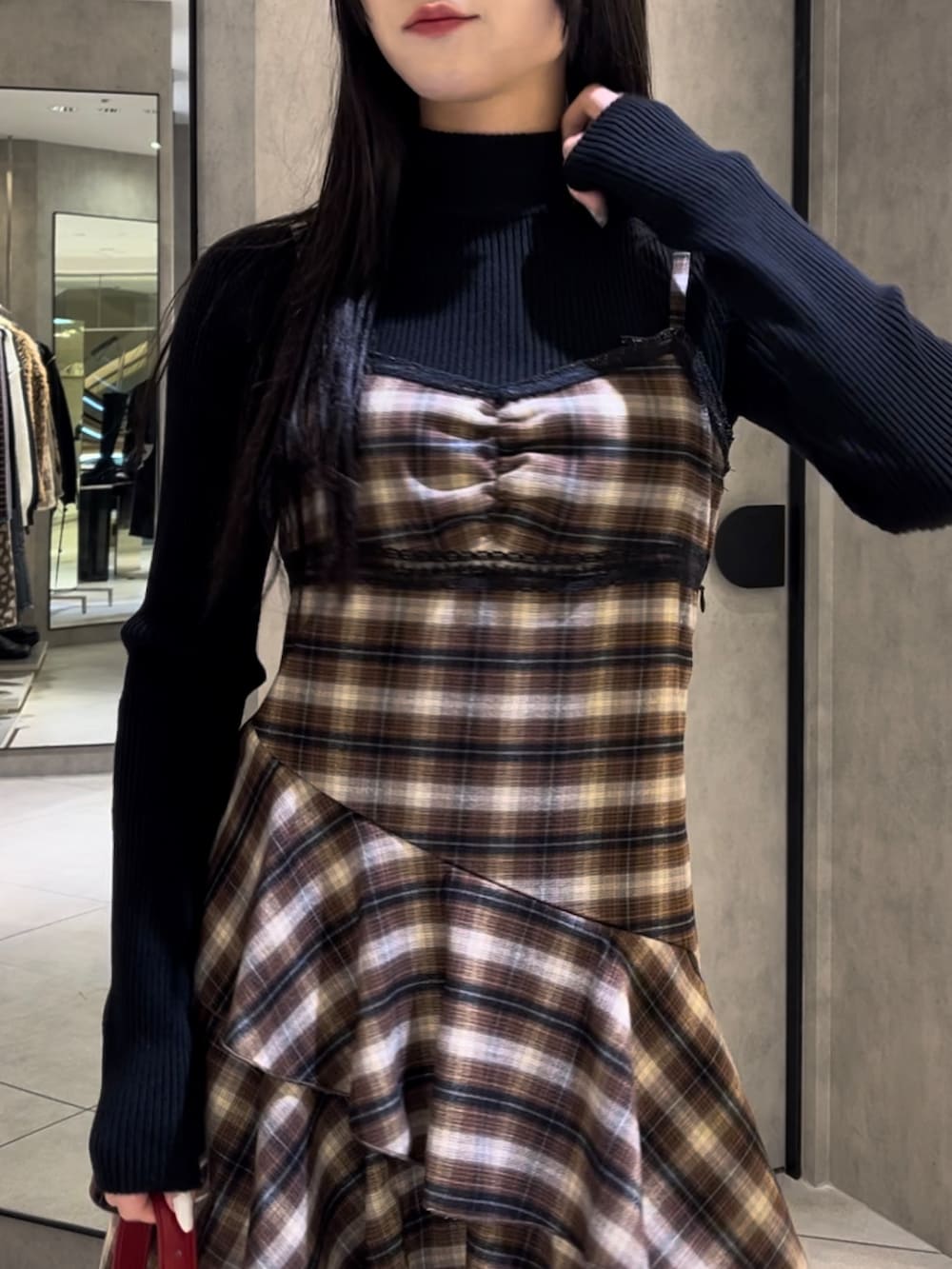 ブラック系のニット/セーター、ベージュ系のワンピース、レッド系のショルダーバッグを着用したレディースの冬コーディネートの6枚目の写真