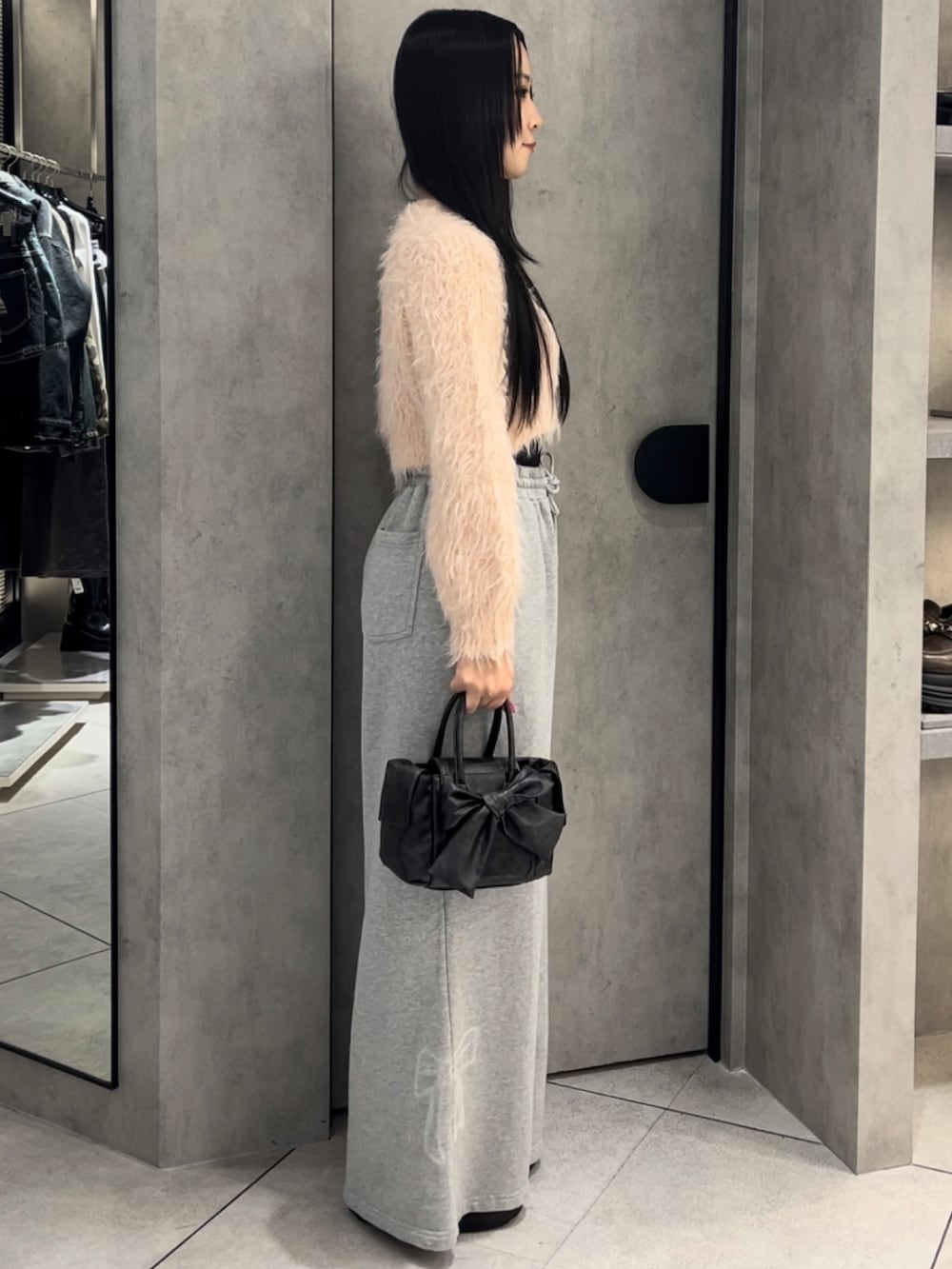 ピンク系のニット/セーター、グレー系のスウェットパンツ、ブラック系のハンドバッグを着用したレディースの冬コーディネートの2枚目の写真