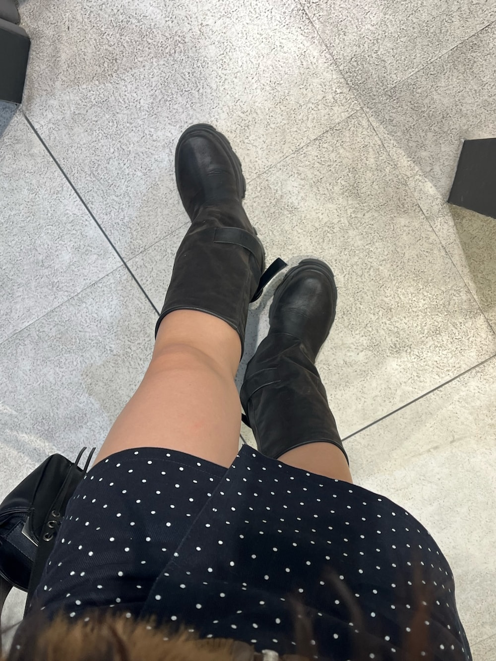 ブラック系のブーツ、ブラック系のハンドバッグ、ブルー系のスカートを着用したレディースの秋コーディネートの6枚目の写真