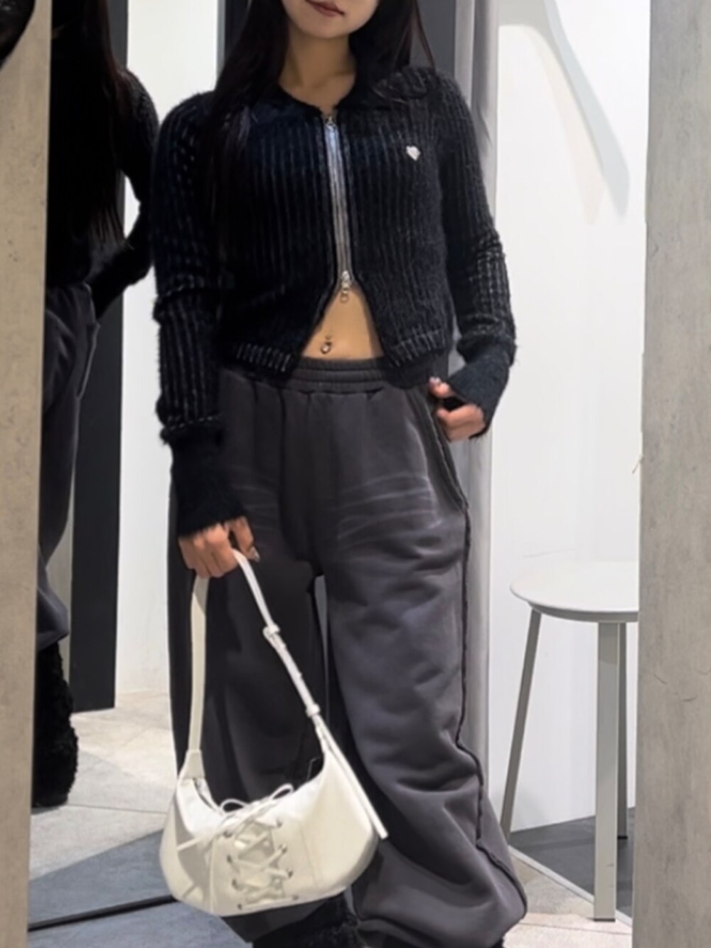 ブラック系のニット/セーター、ホワイト系のショルダーバッグ、ブラック系のブーツを着用したレディースの冬コーディネートの7枚目の写真