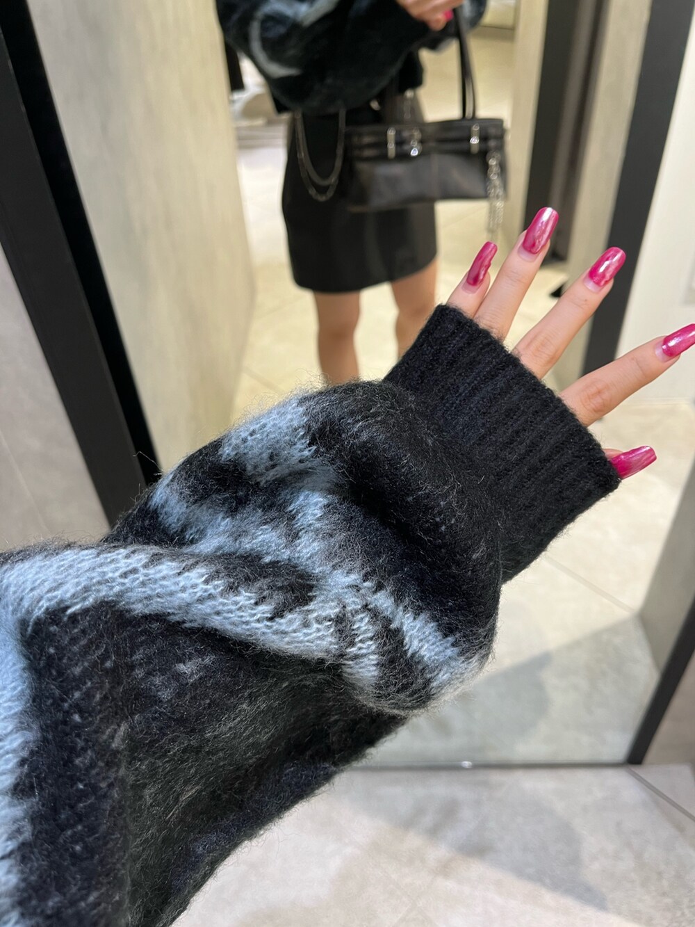 ブラック系のスカート、ブラック系のニット/セーター、ブラック系のショルダーバッグを着用したレディースの秋コーディネートの8枚目の写真