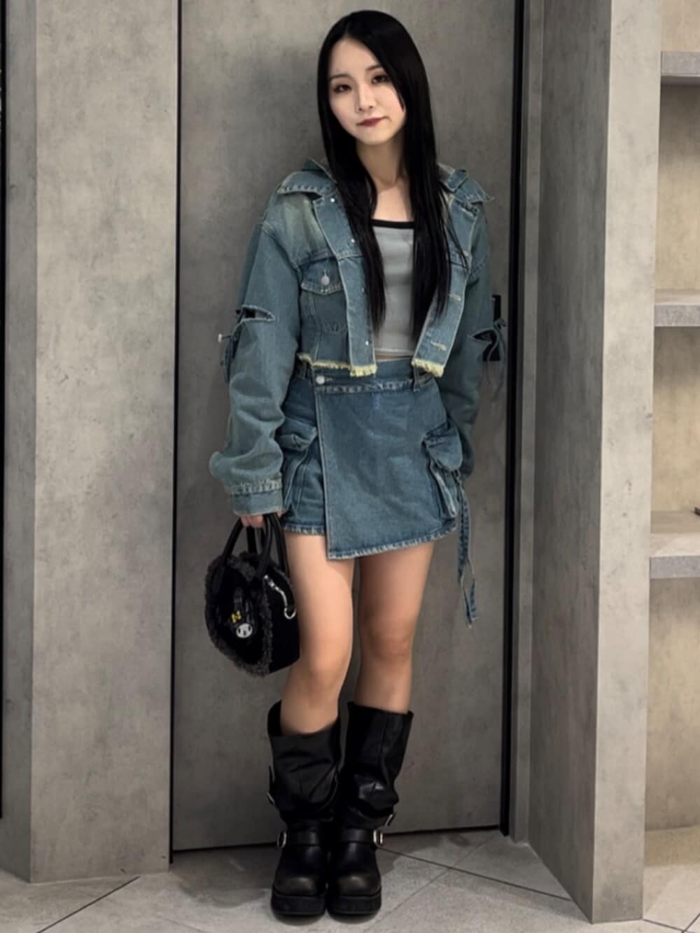 ブラック系のボストンバッグ、ブラック系のブーツ、ブルー系のデニムジャケットを着用したレディースの冬コーディネートの2枚目の写真