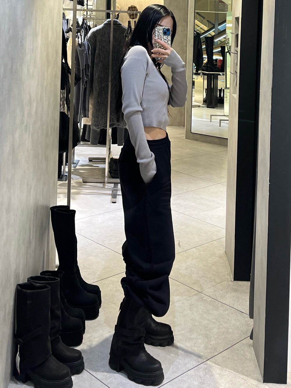 グレー系のニット/セーター、ブラック系のスウェットパンツ、ブラック系のブーツを着用したレディースの冬コーディネートの2枚目の写真