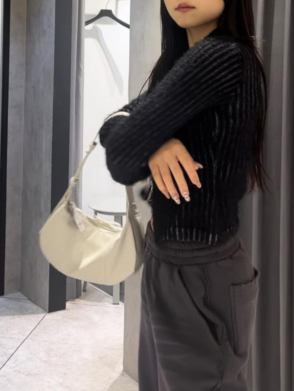 ブラック系のニット/セーター、ホワイト系のショルダーバッグ、ブラック系のブーツを着用したレディースの冬コーディネートの6枚目の写真