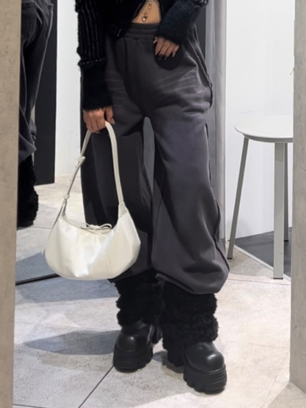 ブラック系のニット/セーター、ホワイト系のショルダーバッグ、ブラック系のブーツを着用したレディースの冬コーディネートの9枚目の写真
