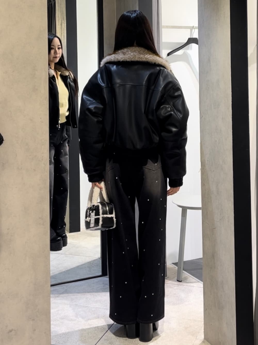 イエロー系のニット/セーター、ブラック系のデニムパンツ、ブラック系のハンドバッグを着用したレディースの冬コーディネートの3枚目の写真