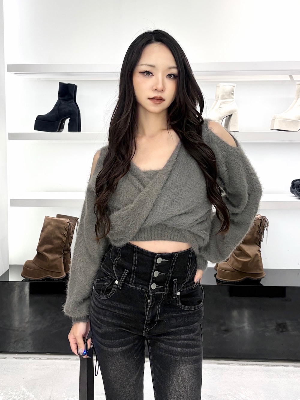 グレー系のニット/セーター、ブラック系のデニムパンツ、ブラック系のショルダーバッグを着用したレディースの秋コーディネートの5枚目の写真