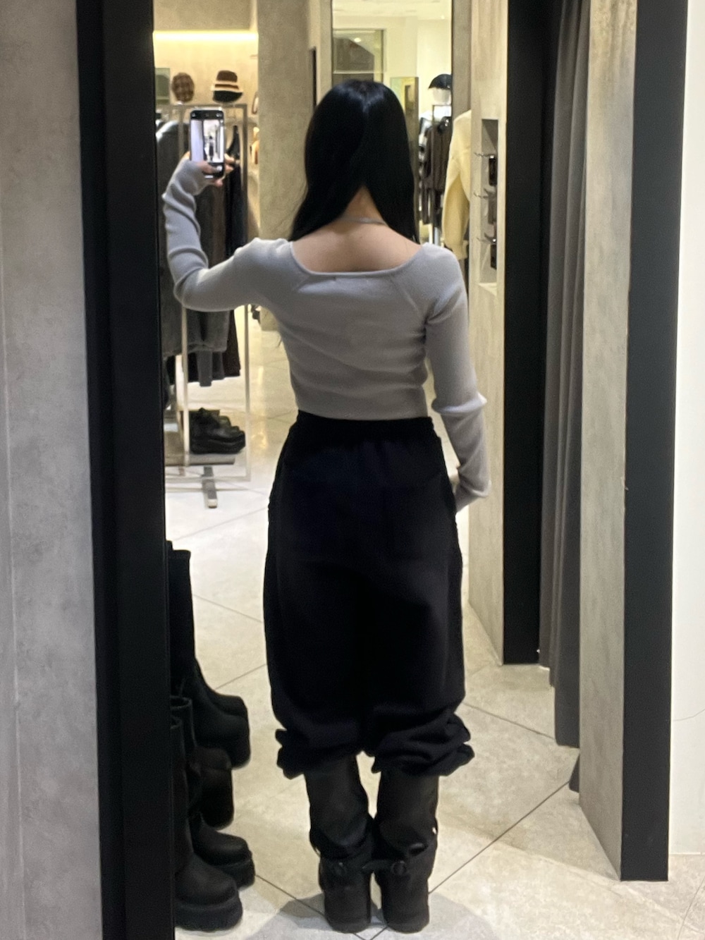 グレー系のニット/セーター、ブラック系のスウェットパンツ、ブラック系のブーツを着用したレディースの冬コーディネートの3枚目の写真