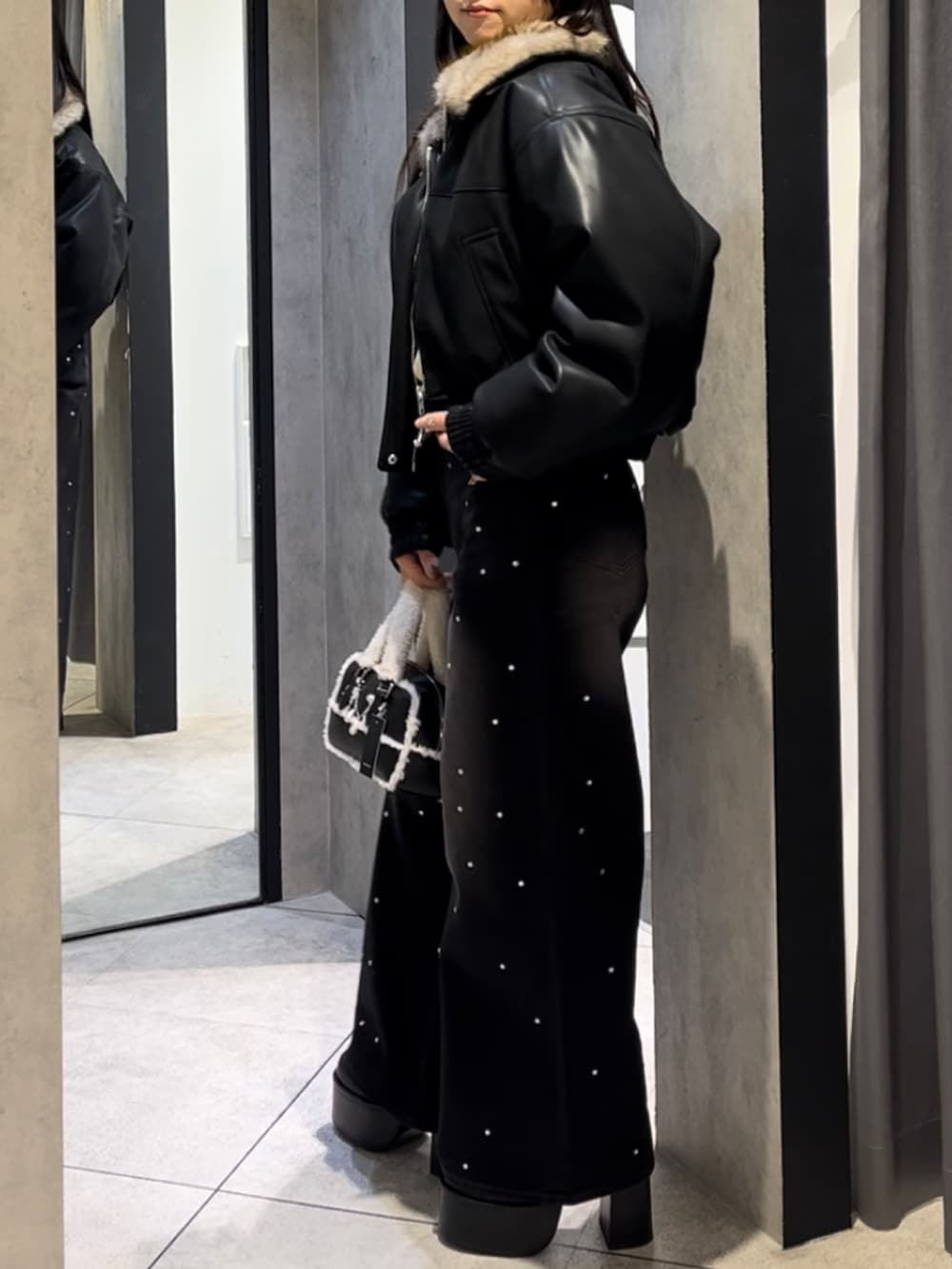 イエロー系のニット/セーター、ブラック系のデニムパンツ、ブラック系のハンドバッグを着用したレディースの冬コーディネートの2枚目の写真