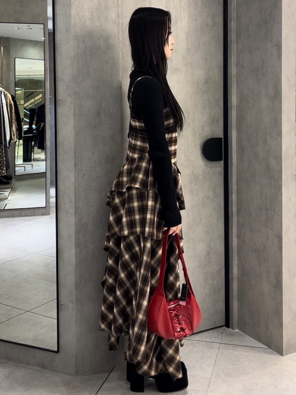 ブラック系のニット/セーター、ベージュ系のワンピース、レッド系のショルダーバッグを着用したレディースの冬コーディネートの2枚目の写真