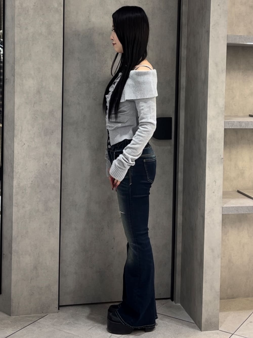 グレー系のニット/セーター、ブルー系のデニムパンツ、ブラック系のブーツを着用したレディースの冬コーディネートの2枚目の写真