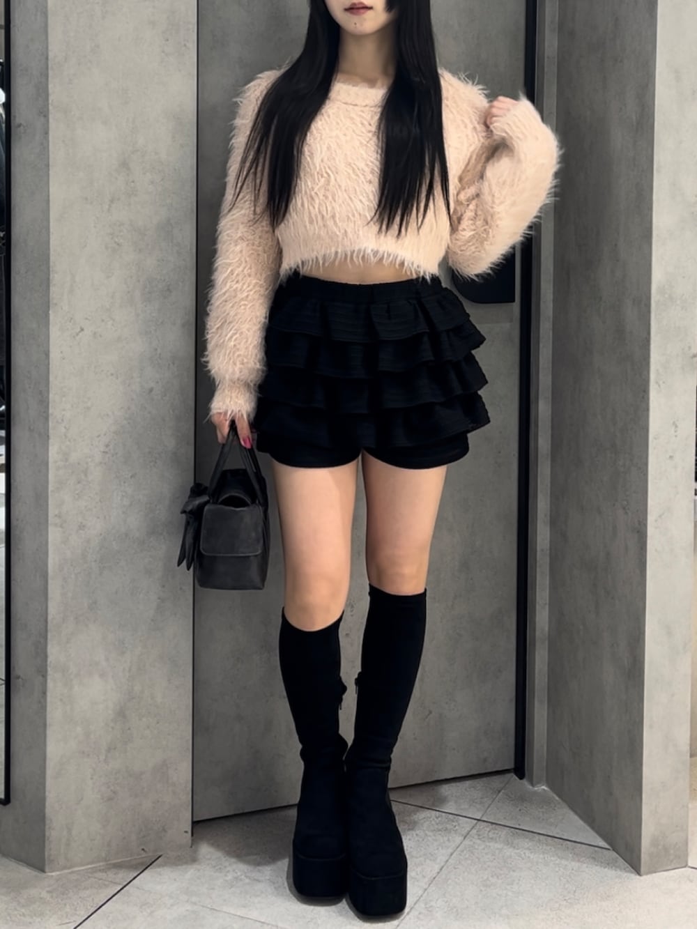 ピンク系のニット/セーター、ブラック系のハンドバッグ、ブラック系のその他パンツを着用したレディースの冬コーディネートの2枚目の写真