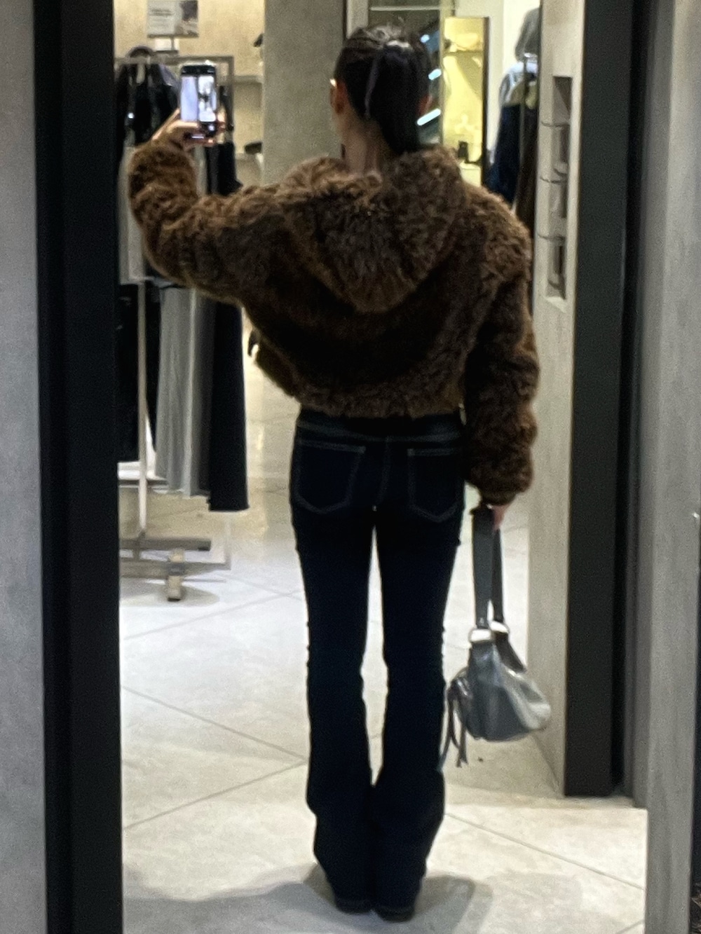 ブラウン系のブルゾン、ブルー系のデニムパンツ、ブラック系のブーツを着用したレディースの秋コーディネートの5枚目の写真