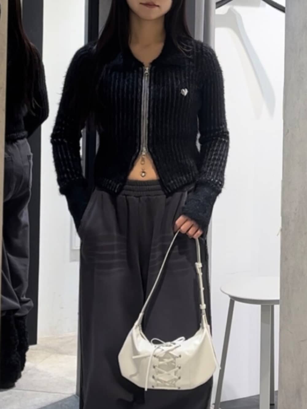 ブラック系のニット/セーター、ホワイト系のショルダーバッグ、ブラック系のブーツを着用したレディースの冬コーディネートの4枚目の写真