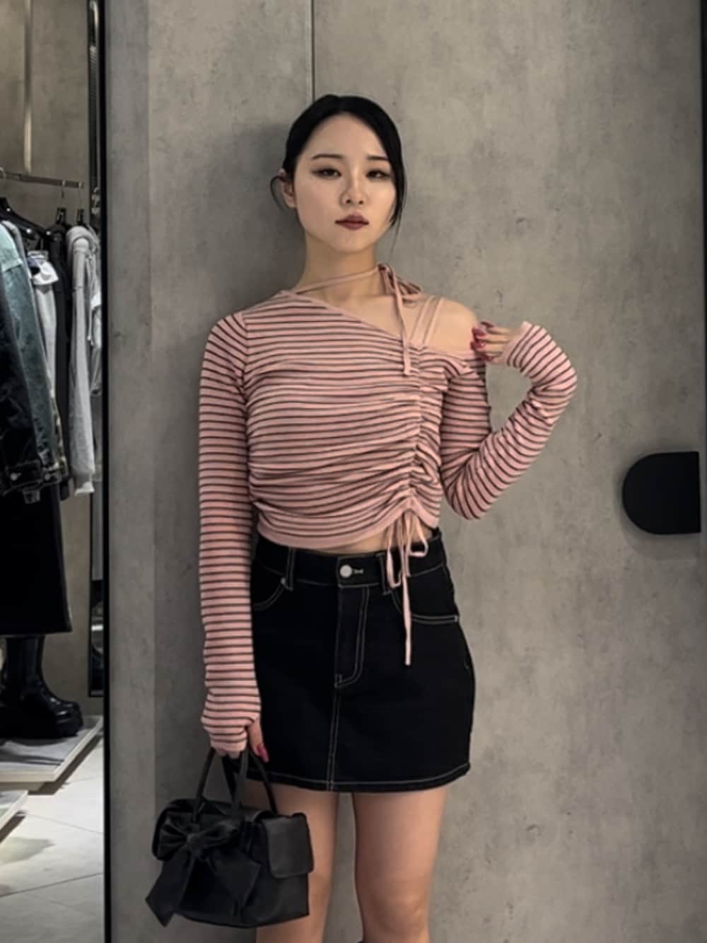 ピンク系のニット/セーター、ブルー系のスカート、ブラウン系のハンドバッグを着用したレディースの冬コーディネートの4枚目の写真