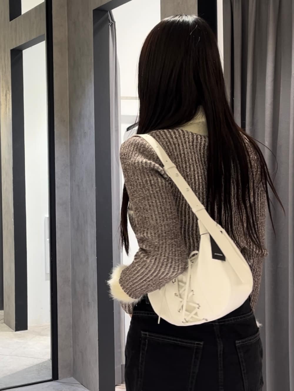 ブラウン系のニット/セーター、ブラック系のスカート、ホワイト系のショルダーバッグを着用したレディースの冬コーディネートの5枚目の写真