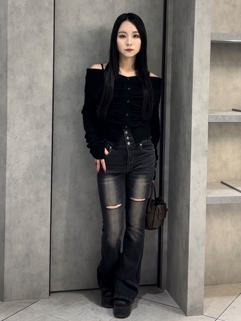 ブラック系のニット/セーター、ブラック系のデニムパンツ、ブラウン系のハンドバッグを着用したレディースの冬コーディネートの2枚目の写真