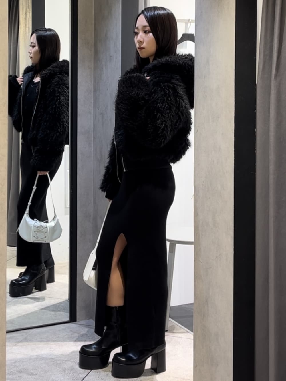 ブラック系のブルゾン、ブラック系のワンピース、ホワイト系のショルダーバッグを着用したレディースの冬コーディネートの5枚目の写真