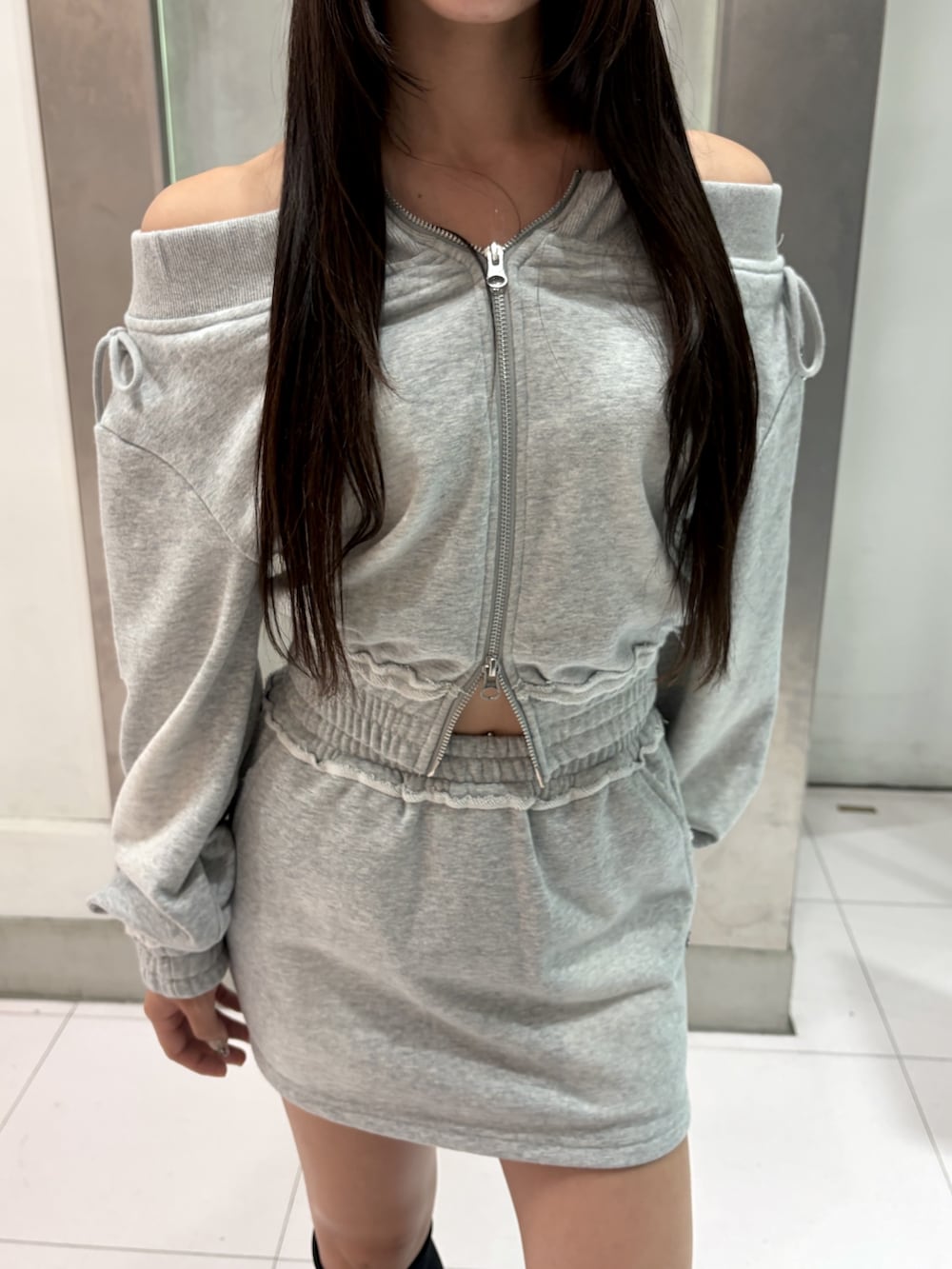 グレー系のTシャツ/カットソー、グレー系のスカート、ブラック系のブーツを着用したレディースの秋コーディネートの5枚目の写真