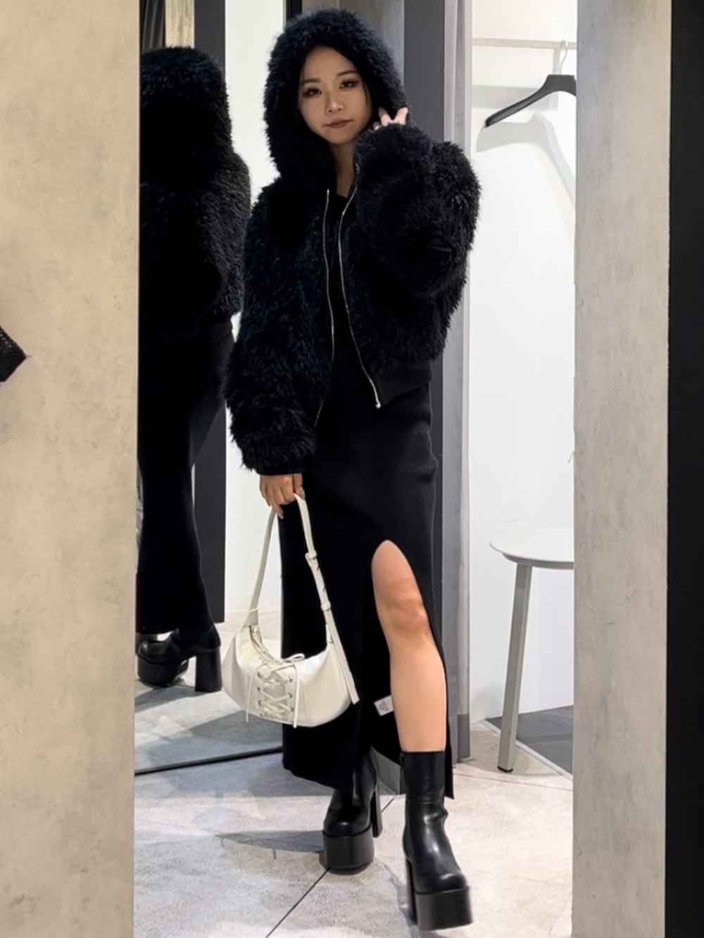 ブラック系のブルゾン、ブラック系のワンピース、ホワイト系のショルダーバッグを着用したレディースの冬コーディネートの7枚目の写真