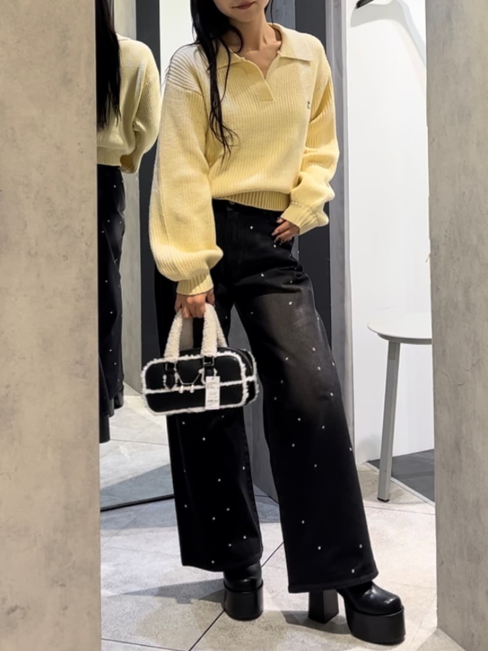 イエロー系のニット/セーター、ブラック系のデニムパンツ、ブラック系のハンドバッグを着用したレディースの冬コーディネートの5枚目の写真