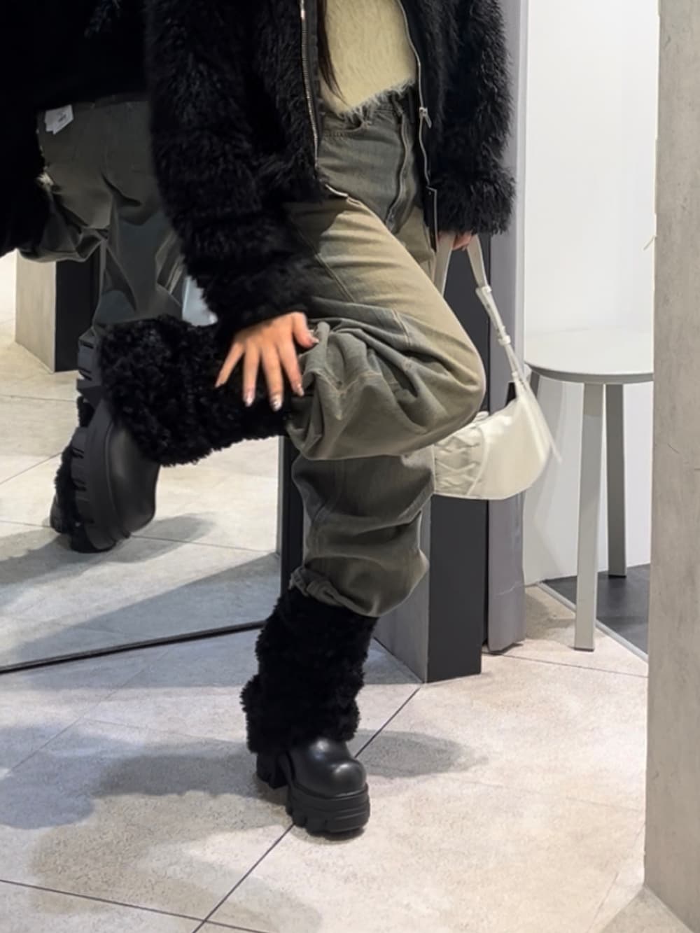 ブラック系のブルゾン、ホワイト系のニット/セーター、ブルー系のデニムパンツを着用したレディースの冬コーディネートの8枚目の写真