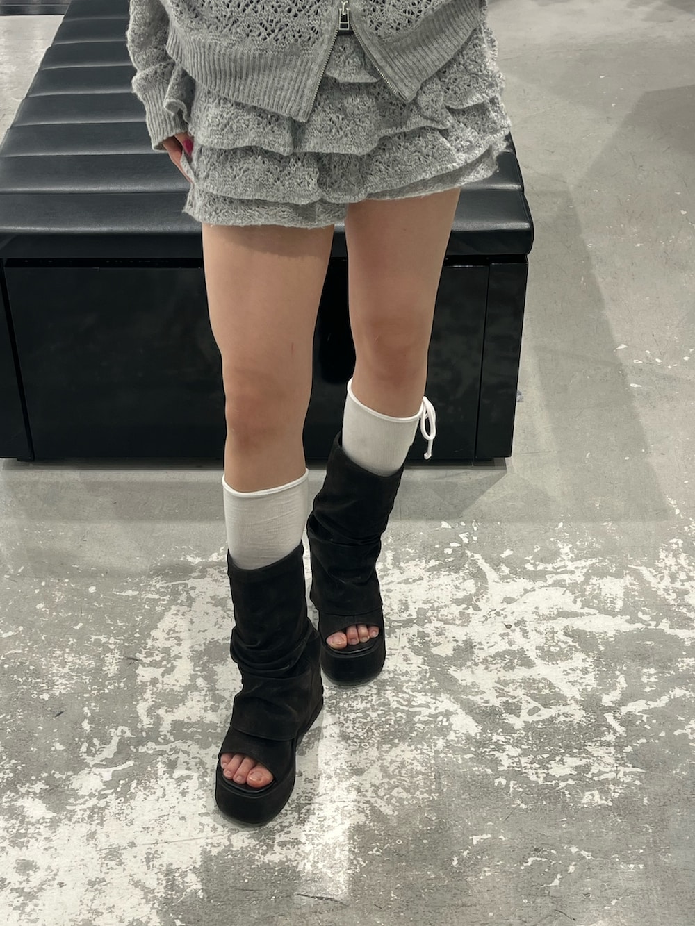 グレー系のパーカー、グレー系のスカート、ブラック系のサンダルを着用したレディースの春コーディネートの8枚目の写真
