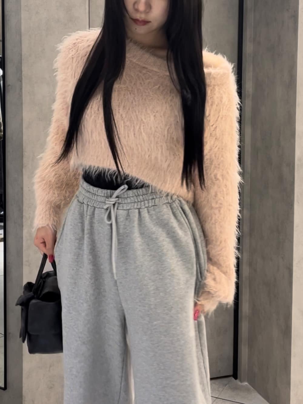 ピンク系のニット/セーター、グレー系のスウェットパンツ、ブラック系のハンドバッグを着用したレディースの冬コーディネートの4枚目の写真