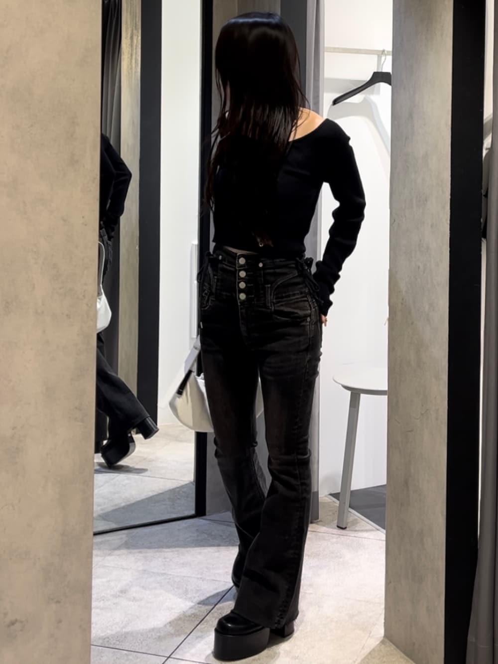 ブラック系のニット/セーター、ブラック系のデニムパンツ、ホワイト系のショルダーバッグを着用したレディースの冬コーディネートの9枚目の写真