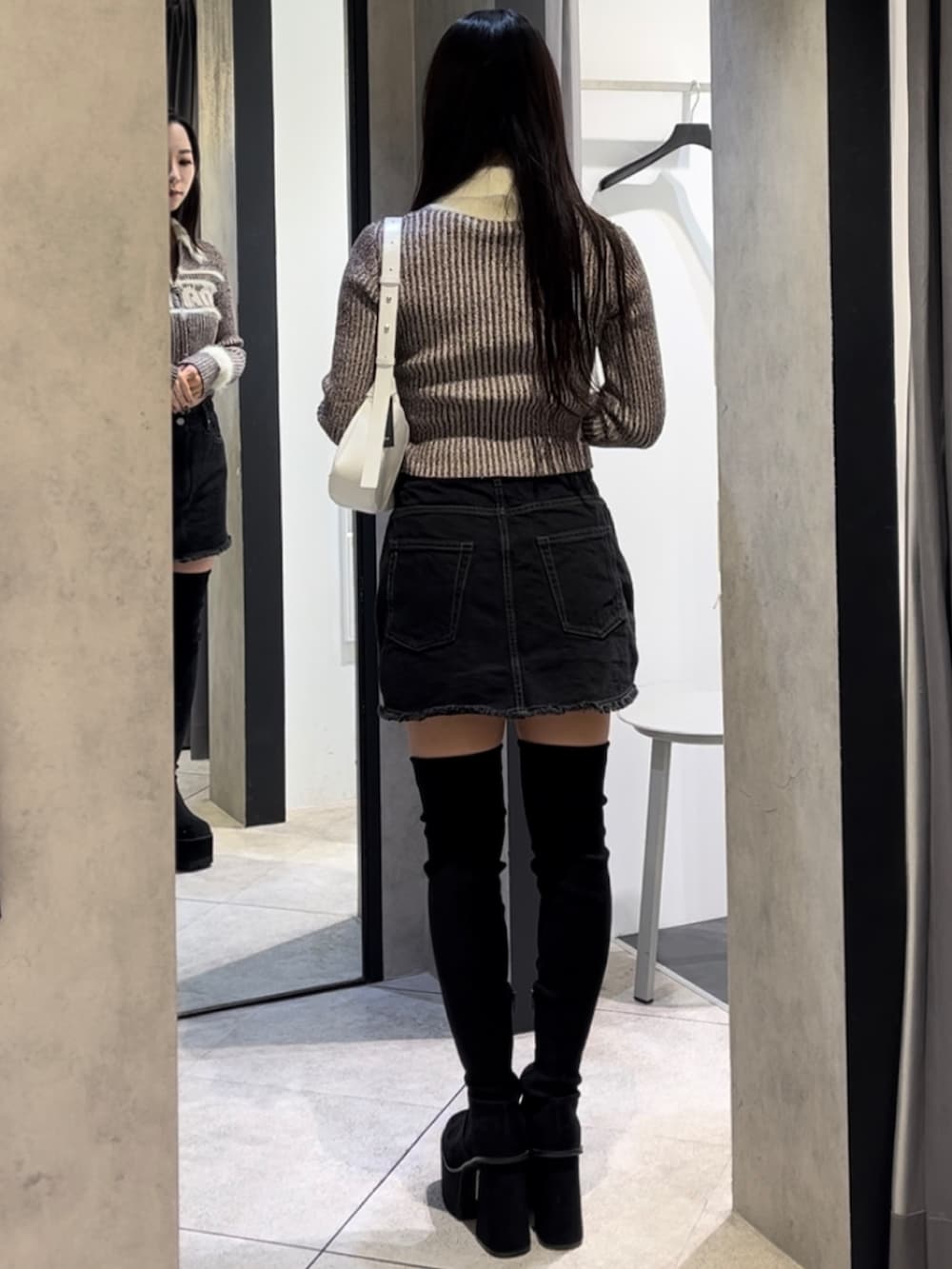 ブラウン系のニット/セーター、ブラック系のスカート、ホワイト系のショルダーバッグを着用したレディースの冬コーディネートの3枚目の写真