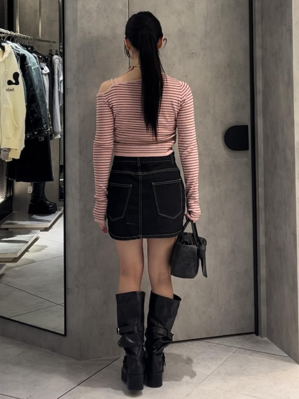 ピンク系のニット/セーター、ブルー系のスカート、ブラウン系のハンドバッグを着用したレディースの冬コーディネートの3枚目の写真