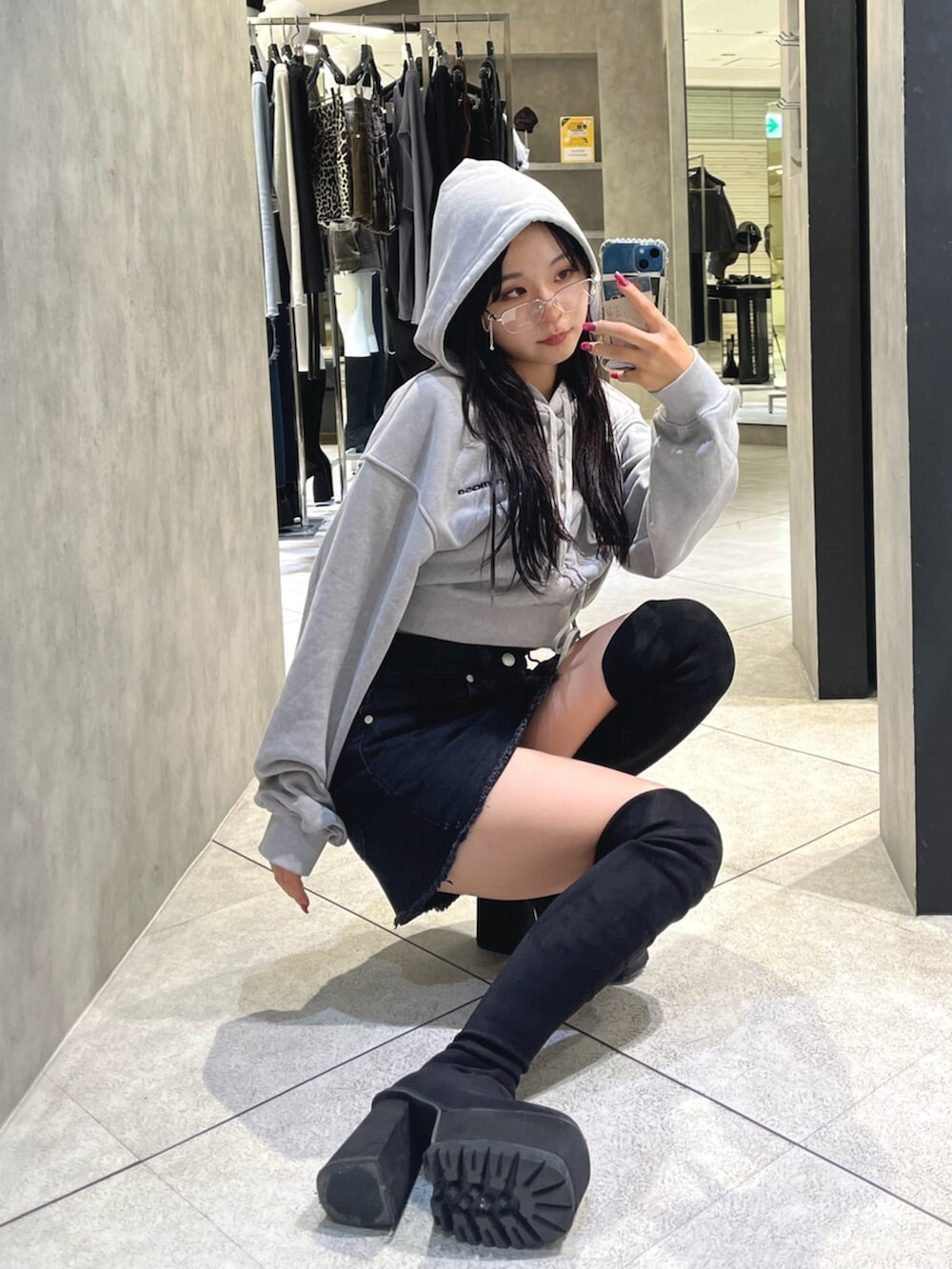 ブラック系のブーツ、グレー系のパーカー、ブラック系のスカートを着用したレディースの秋コーディネートの10枚目の写真