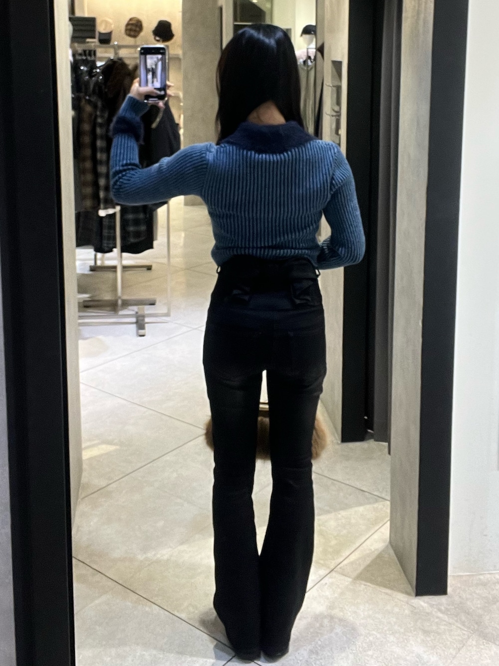 ブルー系のニット/セーター、ブラック系のデニムパンツ、ベージュ系のショルダーバッグを着用したレディースの冬コーディネートの3枚目の写真